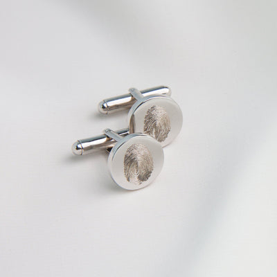 Silver fingerprint cufflinks on a light gray background